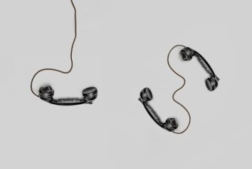 pexels-photo-821754-821754 Two vintage black telephone handsets connected by cords on gray background.
